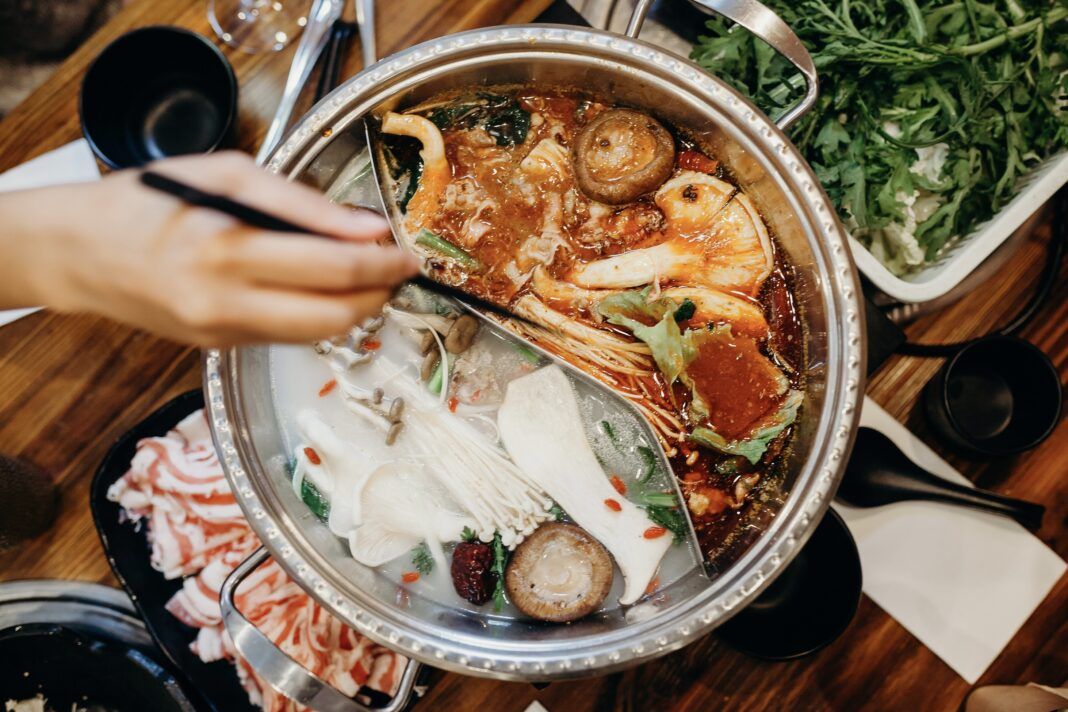 Korean hot pot meal. Hands taking food with chopsticks.