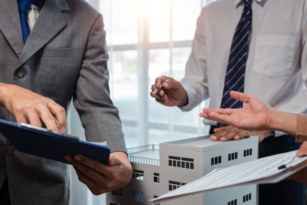 Real estate agents discussing property investment with building architectural model